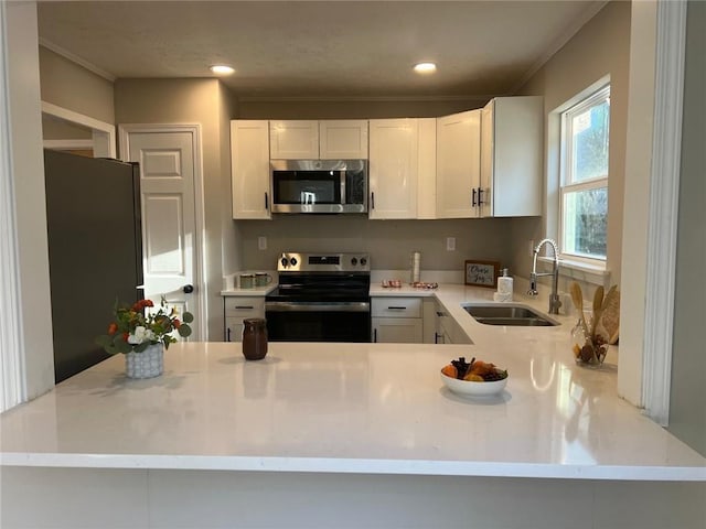 kitchen featuring white cabinetry, appliances with stainless steel finishes, kitchen peninsula, and sink