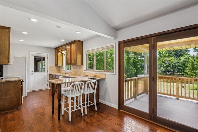12 Windsor Way, Newnan, GA 30263 - kitchen featuring light stone countertops, dark wood-type flooring, a peninsula, backsplash, and recessed lighting