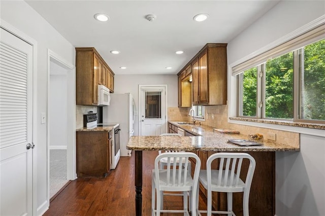 12 Windsor Way, Newnan, GA 30263 - kitchen featuring white appliances, light stone countertops, backsplash, dark wood-type flooring, and recessed lighting