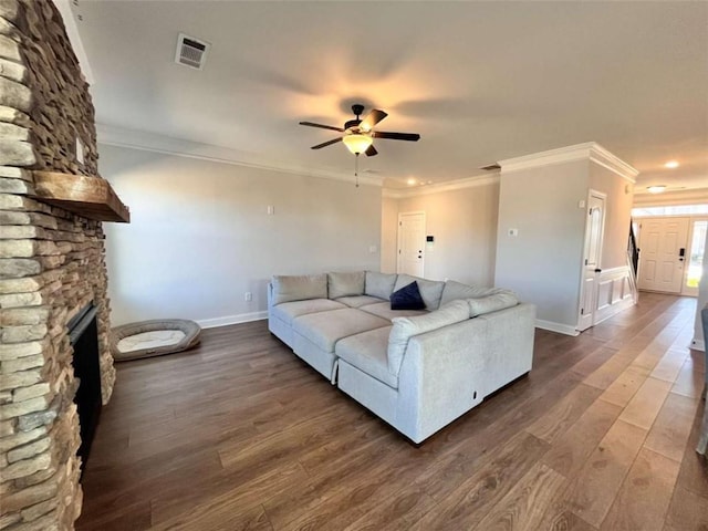 living room featuring dark hardwood / wood-style flooring, a fireplace, ornamental molding, and ceiling fan