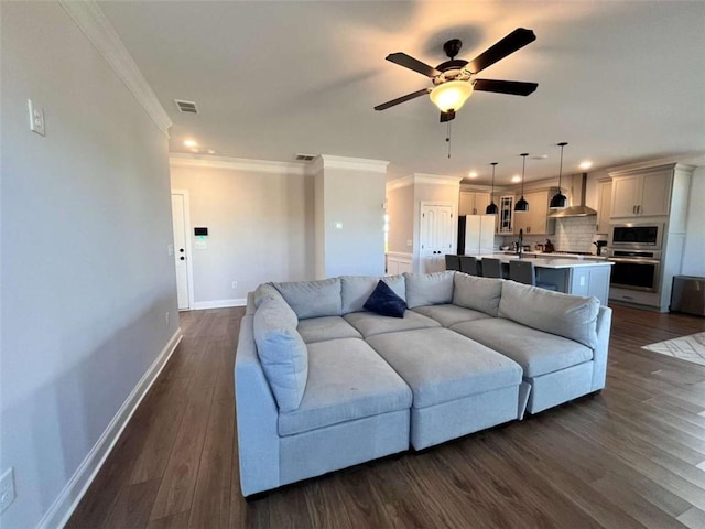 living room with crown molding, dark wood-type flooring, and ceiling fan