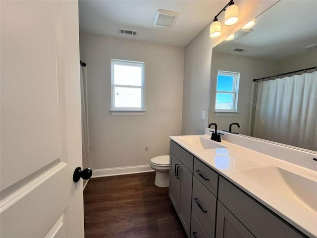 bathroom with wood-type flooring, walk in shower, vanity, and toilet