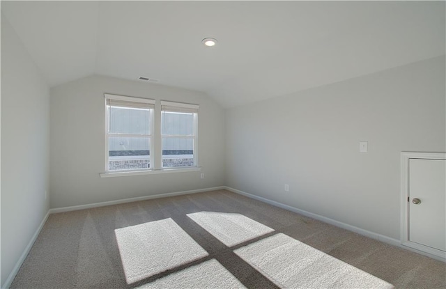 additional living space featuring vaulted ceiling and light colored carpet