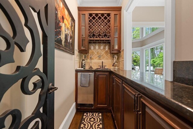 bar featuring dark hardwood / wood-style floors, crown molding, dark stone counters, and tasteful backsplash