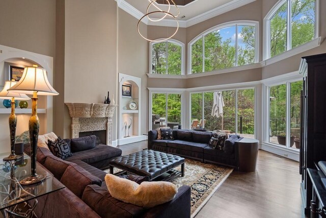 living room featuring crown molding, hardwood / wood-style floors, a chandelier, and a high ceiling