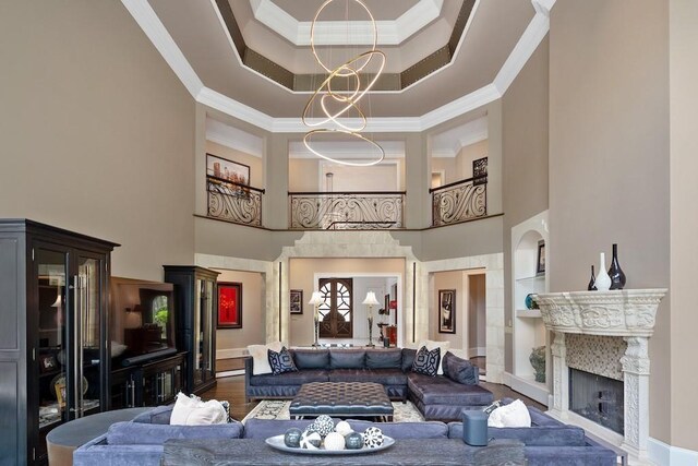 living room featuring dark wood-type flooring, crown molding, built in features, a towering ceiling, and a premium fireplace