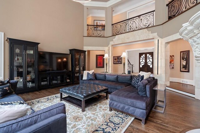 living room with crown molding, french doors, a towering ceiling, and dark wood-type flooring