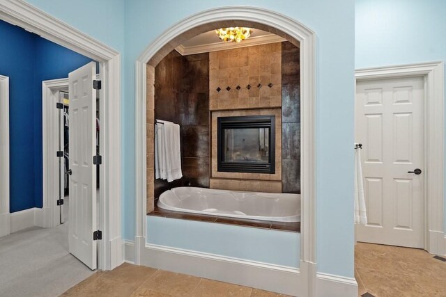 bathroom with a tile fireplace, tile patterned floors, a bathing tub, and ornamental molding