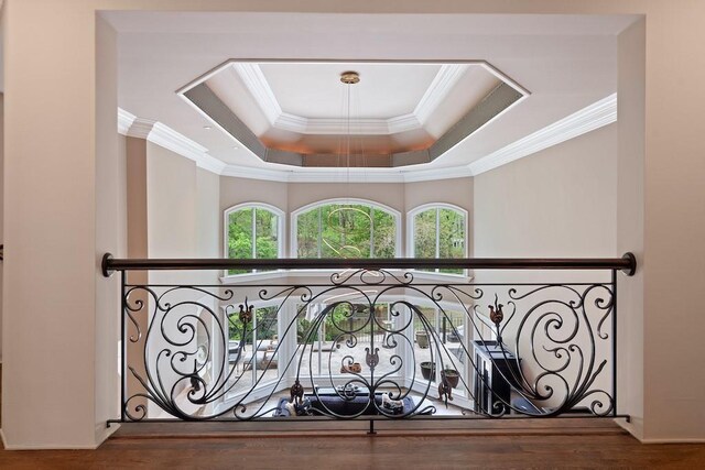 interior space with wood-type flooring, ornamental molding, and a tray ceiling