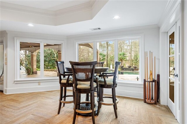 dining room with crown molding, plenty of natural light, and light parquet floors