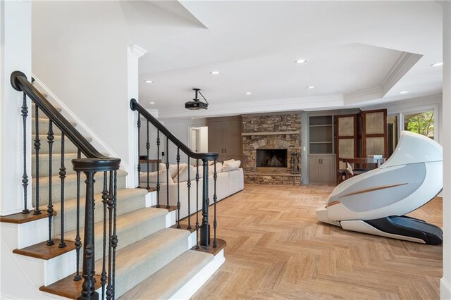 interior space with a raised ceiling, crown molding, parquet flooring, and a fireplace