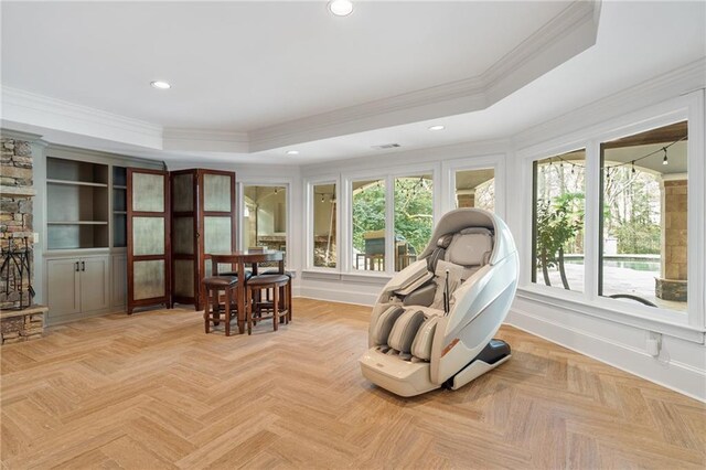 living area featuring a raised ceiling, ornamental molding, and light parquet flooring