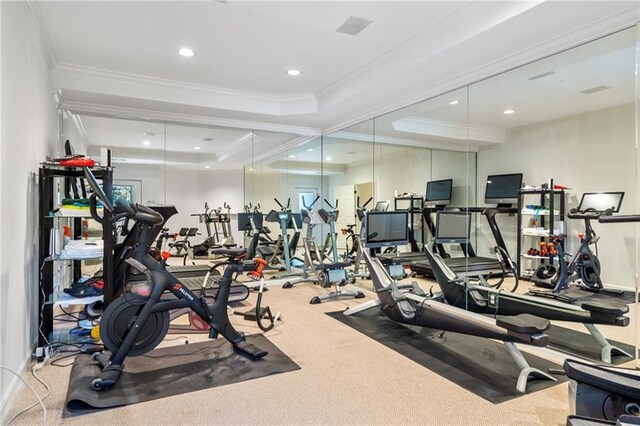 gym featuring carpet, a tray ceiling, and ornamental molding