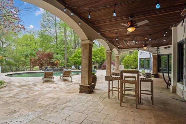 view of patio / terrace featuring a fenced in pool, an outdoor bar, and ceiling fan