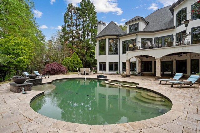 exterior space featuring a pool with hot tub, a balcony, and a patio