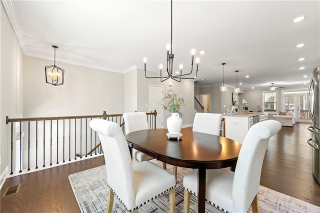 dining space with recessed lighting, ceiling fan with notable chandelier, visible vents, ornamental molding, and dark wood finished floors