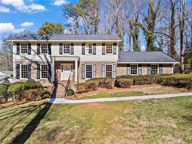 colonial home with brick siding and a front yard