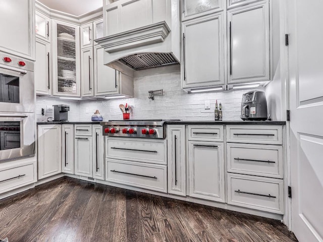 5039 Towne Lake Hls N, Woodstock, GA 30189 - kitchen featuring appliances with stainless steel finishes, dark countertops, decorative backsplash, and glass insert cabinets