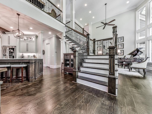 5039 Towne Lake Hls N, Woodstock, GA 30189 - staircase featuring ornamental molding, a towering ceiling, ceiling fan, wood finished floors, and baseboards