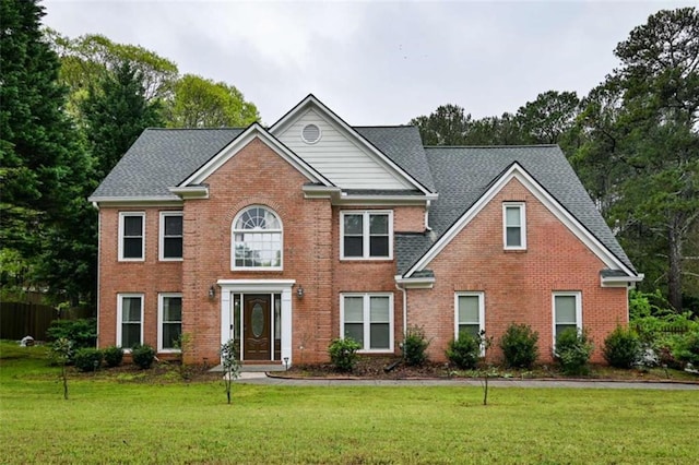 colonial house featuring a front lawn and brick siding
