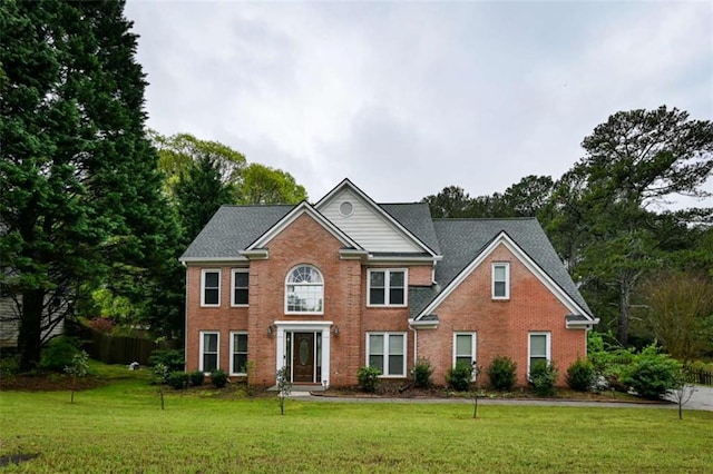 colonial home with fence, a front lawn, and brick siding