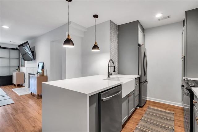 kitchen with stainless steel appliances, sink, hanging light fixtures, and kitchen peninsula