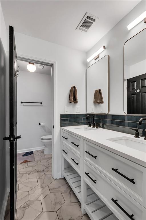 bathroom featuring vanity, tasteful backsplash, and toilet