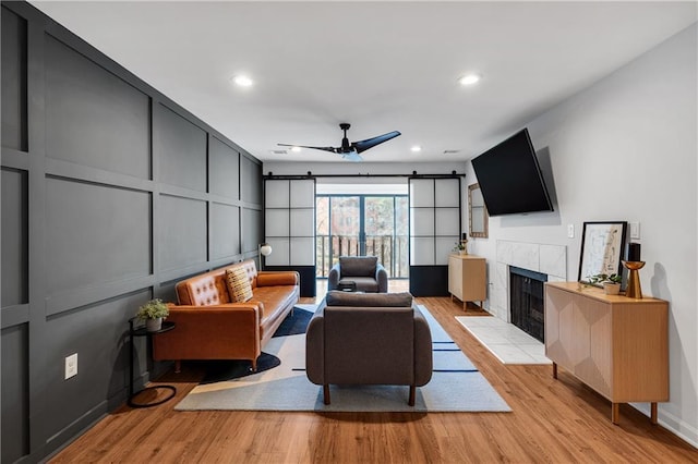 living room featuring ceiling fan, light hardwood / wood-style flooring, and a fireplace