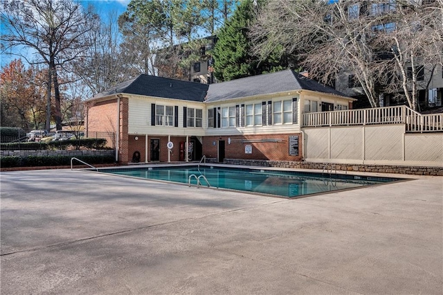 back of house featuring tennis court and a community pool