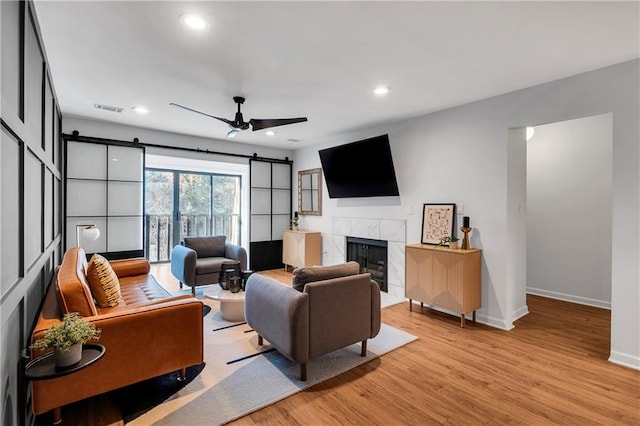 living room with a fireplace, ceiling fan, and light wood-type flooring