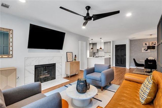 living room featuring a fireplace, ceiling fan, and light hardwood / wood-style floors