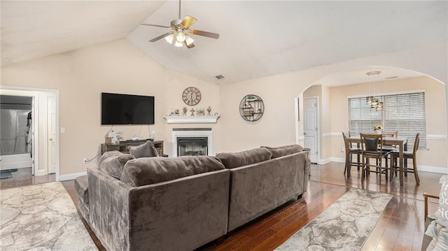 living room featuring lofted ceiling, wood-type flooring, a fireplace, and arched walkways