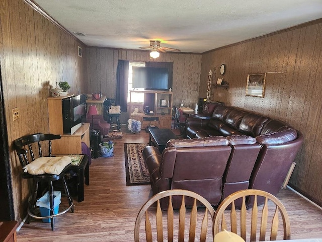 living room with a textured ceiling, ceiling fan, crown molding, and hardwood / wood-style floors