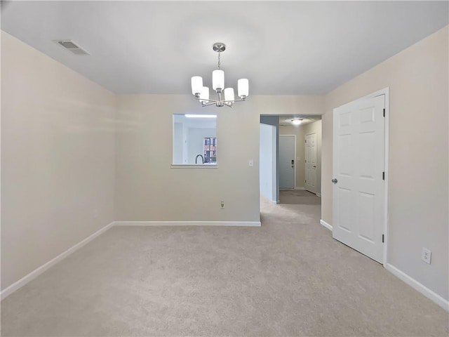 spare room featuring an inviting chandelier, baseboards, visible vents, and light colored carpet