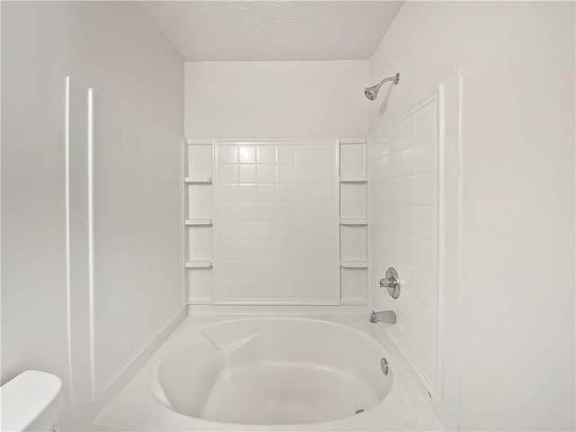 bathroom featuring toilet, a textured ceiling, and shower / bathing tub combination