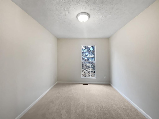 carpeted empty room with visible vents, a textured ceiling, and baseboards