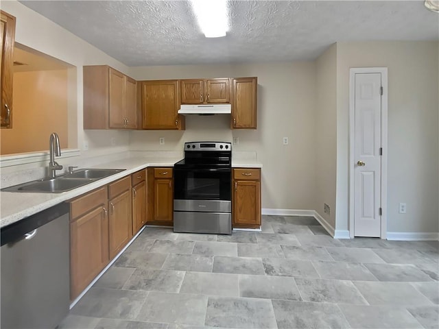 kitchen featuring stainless steel appliances, light countertops, brown cabinetry, a sink, and under cabinet range hood