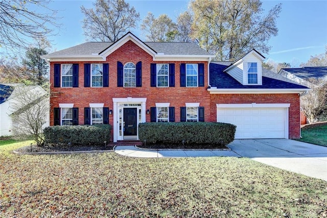 colonial inspired home with driveway, brick siding, a shingled roof, an attached garage, and a front yard