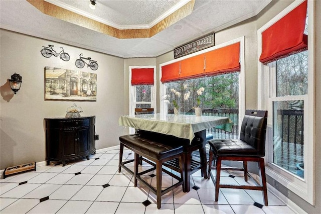 dining area with a textured ceiling, light tile patterned flooring, baseboards, ornamental molding, and a tray ceiling