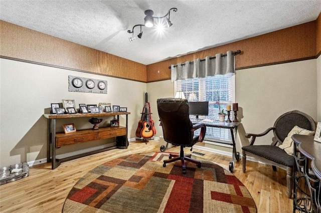 home office featuring a textured ceiling, wood finished floors, and baseboards