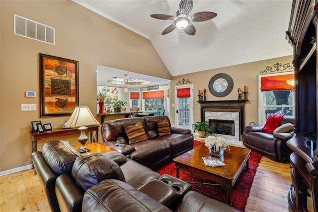 living area with a wealth of natural light, visible vents, vaulted ceiling, and wood finished floors