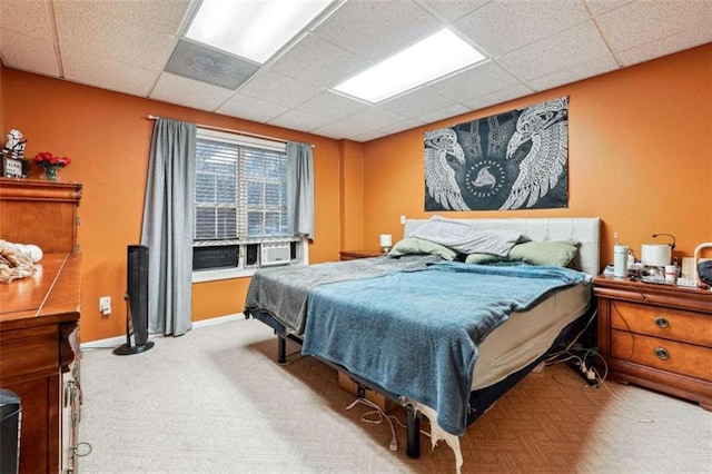 carpeted bedroom featuring a paneled ceiling and baseboards