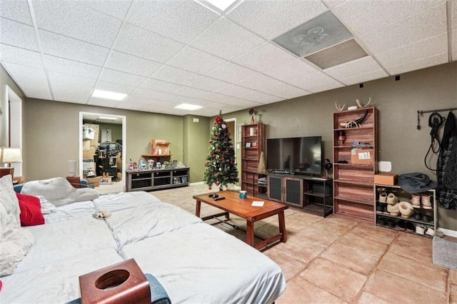 tiled living area featuring a drop ceiling and baseboards