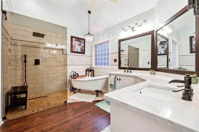 bathroom featuring tile walls, lofted ceiling, a soaking tub, a sink, and a walk in shower