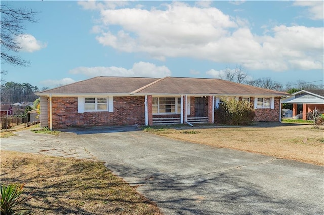 ranch-style home with driveway, a front lawn, and brick siding