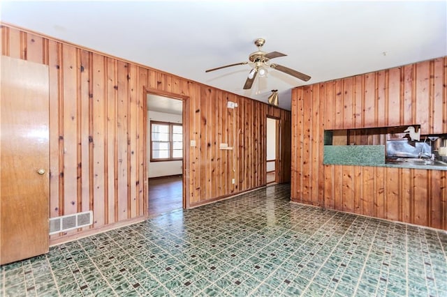 empty room featuring wood walls, visible vents, and tile patterned floors