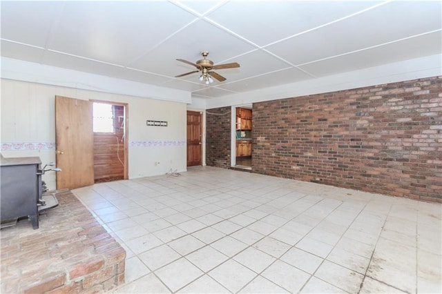 interior space with ceiling fan, brick wall, stairs, and a wood stove