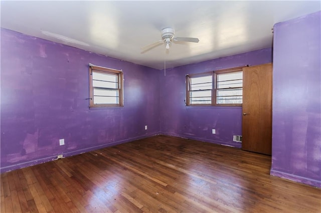 empty room with wood-type flooring, visible vents, baseboards, and a ceiling fan