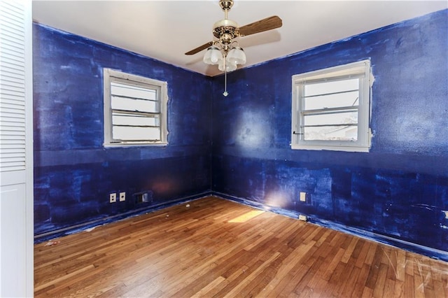 unfurnished room with a healthy amount of sunlight, ceiling fan, and wood finished floors