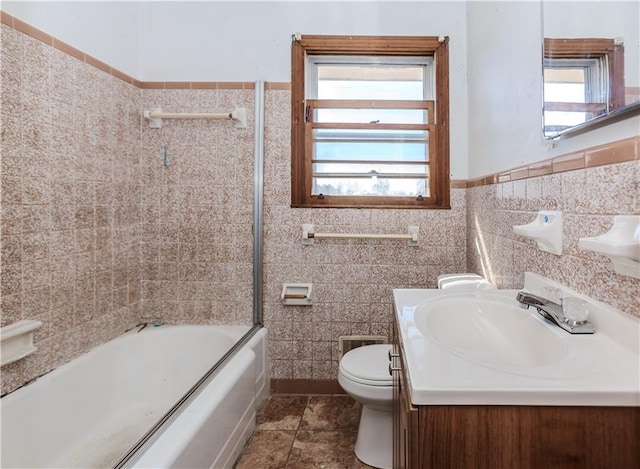 full bath featuring wainscoting, toilet, tile patterned floors,  shower combination, and tile walls